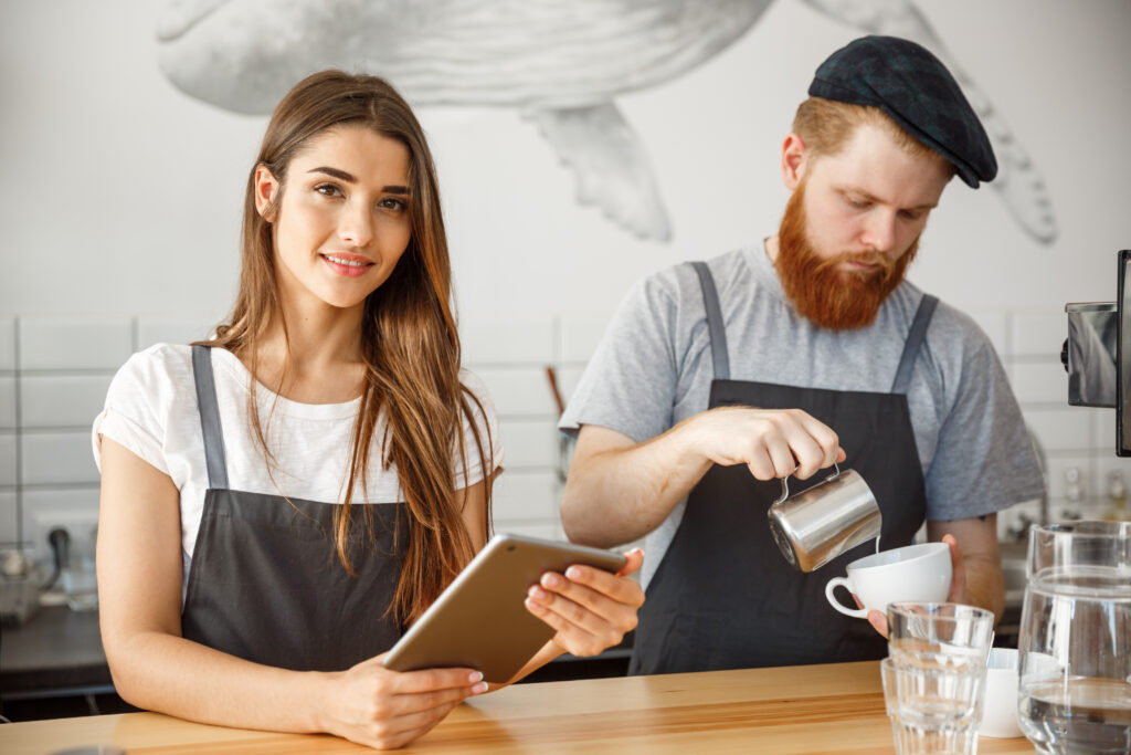 Website SODEW 7 coffee business concept cheerful baristas looking their tablets online orders modern coffee shop